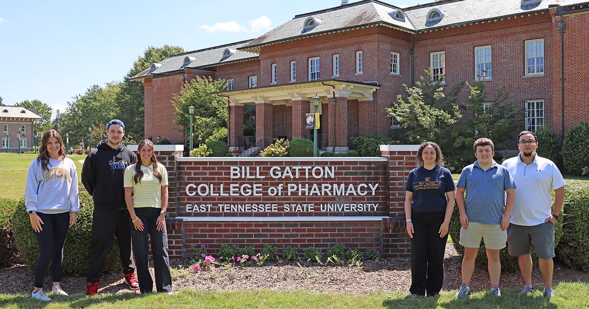 Tutors in front of the ETSU Gatton College of Pharmacy sign.