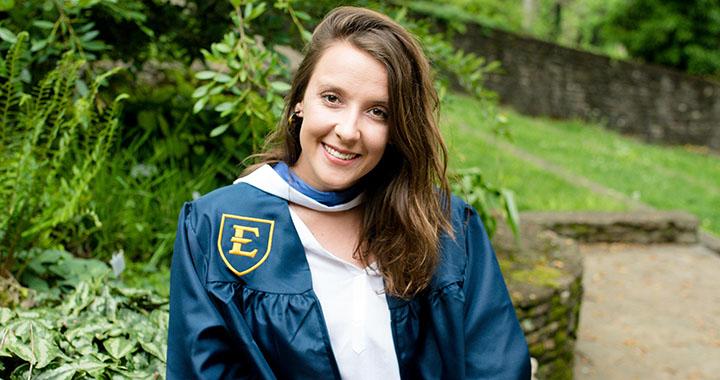 woman poses in graduation gown
