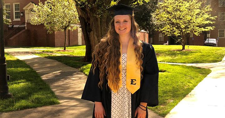 woman poses in cap and gown