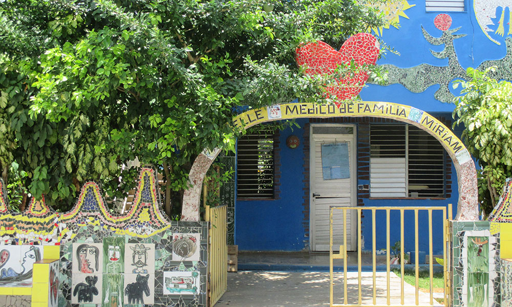 A tile mosaic archway with a mosaic heart atop, reads "Elle Medico de Familia Miriam."