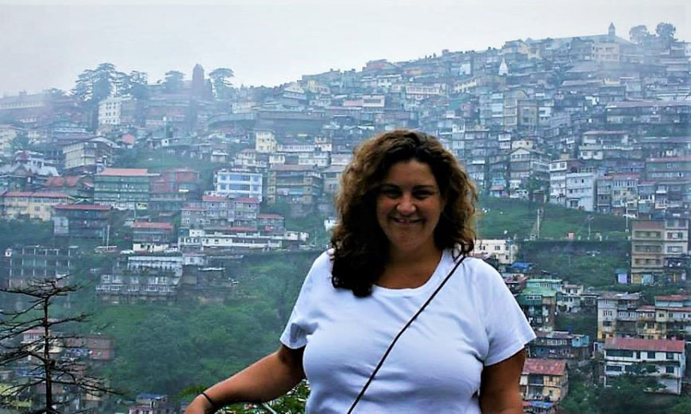 Dr. Schrift poses in front of a bustling, mountainside metropolis.
