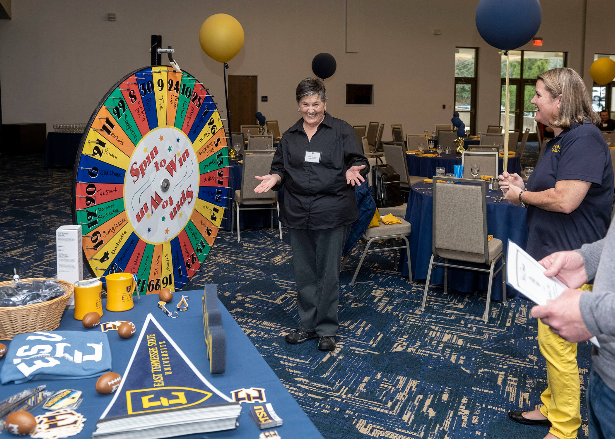 A staff member encourages another employee to spin the wheel to win a prize.