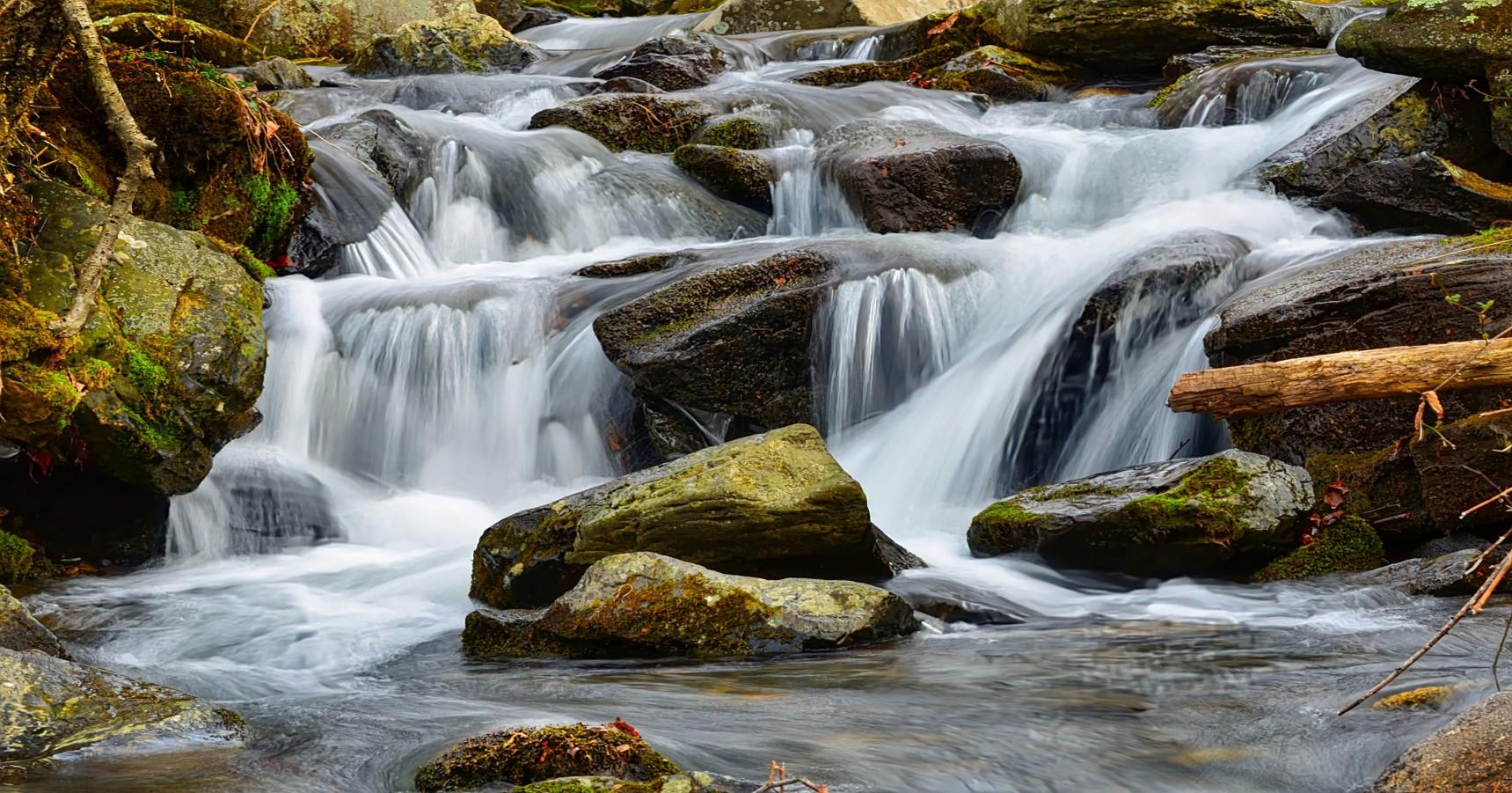 A mountain stream cascades over rocks in the Roan Highlands region.
