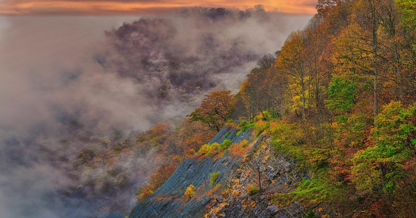Low Clouds are passing through the mountains with trees showing their fall colors