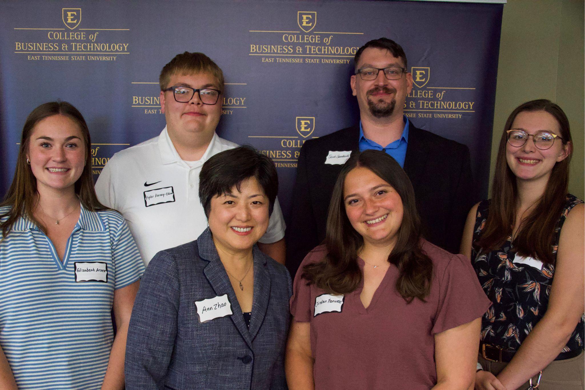 ETSU CBAT members smile in front of a College of Business and Technology backdrop.