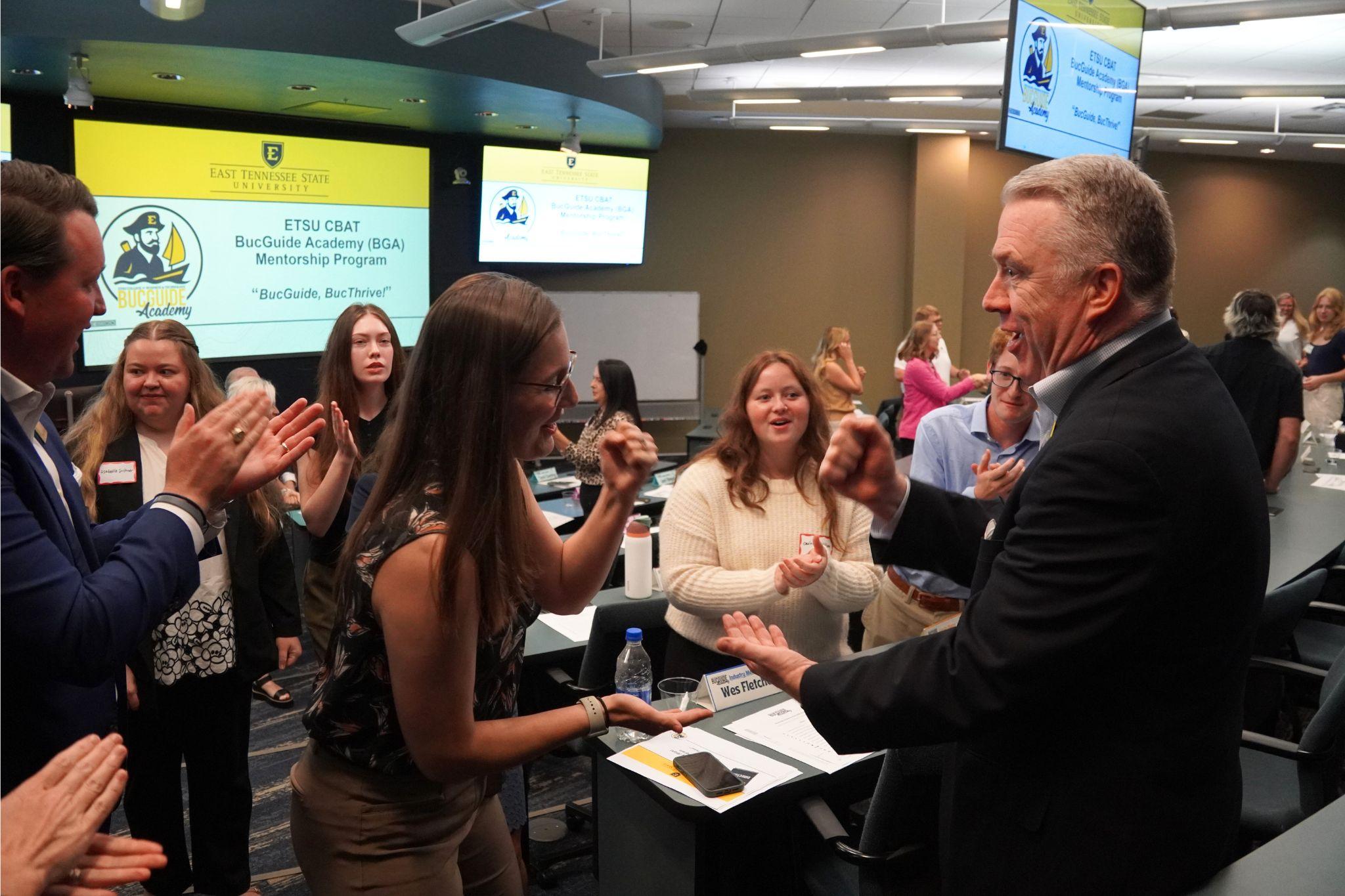 Many East Tennessee State University faculty, staff, students, and industry partners play rock paper scissors at the BucGuide Academy (BGA) meeting.