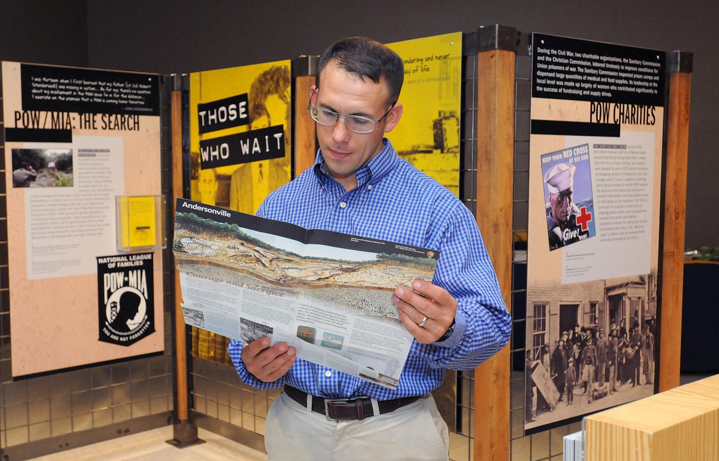 A visitor views supporting material in the 2015 traveling exhibition Victory from Within: The American Prisoner of War Experience.