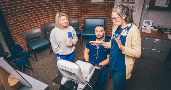 Two ETSU students learning from their instructor how to use audiology equipment at the Center for Outpatient Rehabilitation