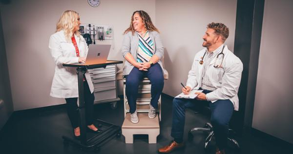 ETSU students in a clinic setting of a patient room, where they are sitting and discussing medical charts with a patient