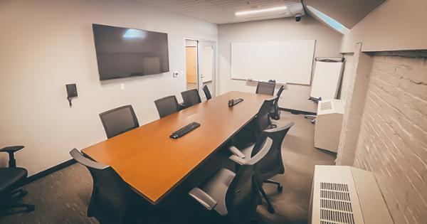 A debriefing room in ETSU's Bishop Hall, where people sit at a conference room table looking at a central screen to review simulations