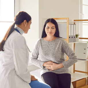 Patient suffering from stomach ache having consultation with female doctor in medical office. Young woman visiting gastroenterologist, gynecologist, therapist, GP in medical clinic.