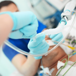 Medical doctor with assistant intubates male patient in the critical care unit.