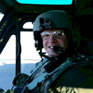Ajay McLaughlin in uniform, smiling at the camera in a plane.