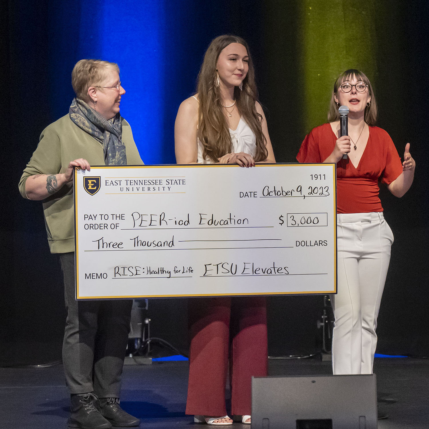 Leah Loveday and Rebecca Pearson on stage with their big check