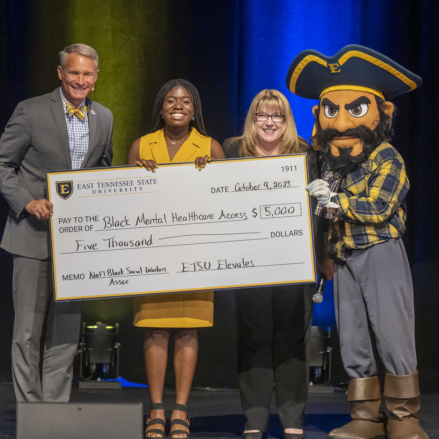 Sarah Mohammed holds her check and stands with President Noland and Bucky