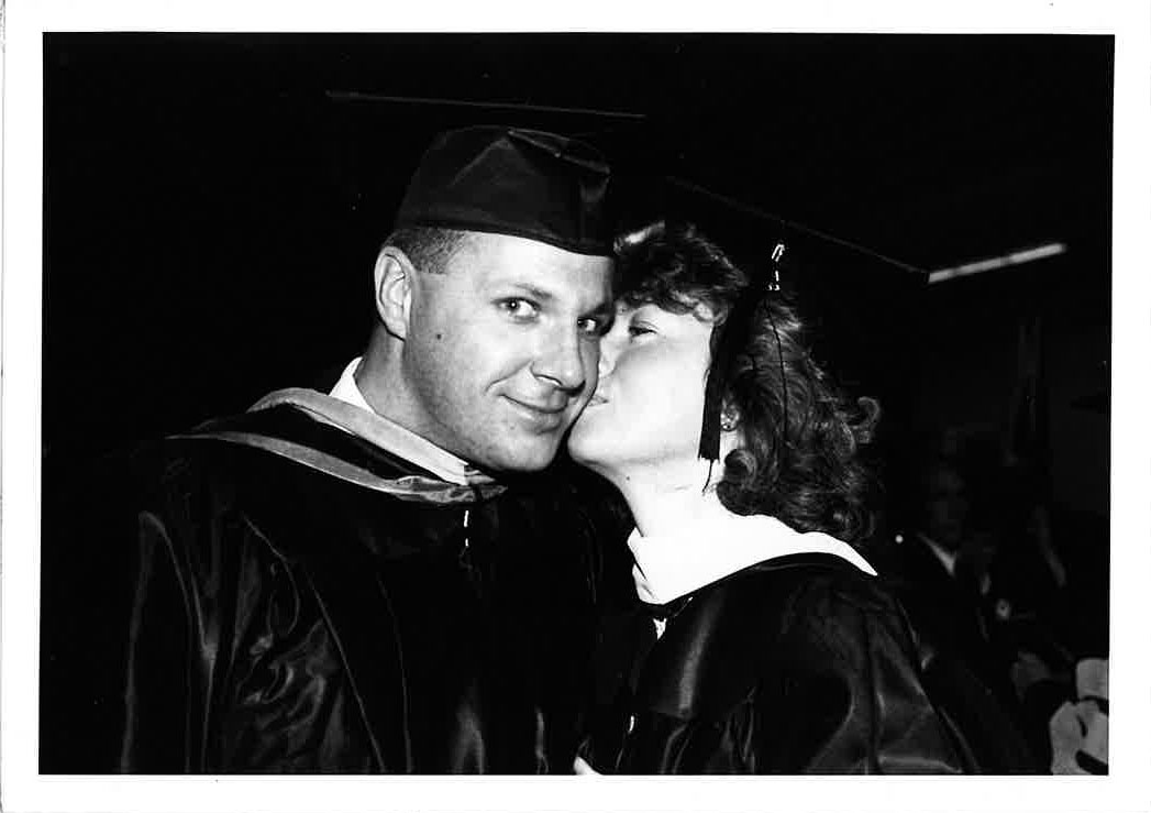 Vickie Connolly kisses Mike Connolly on the cheek. He is wearing a cap and gown.