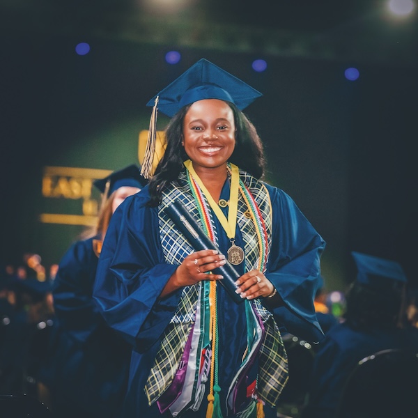 A Roan Scholar wears her cap and gown at Commencement.