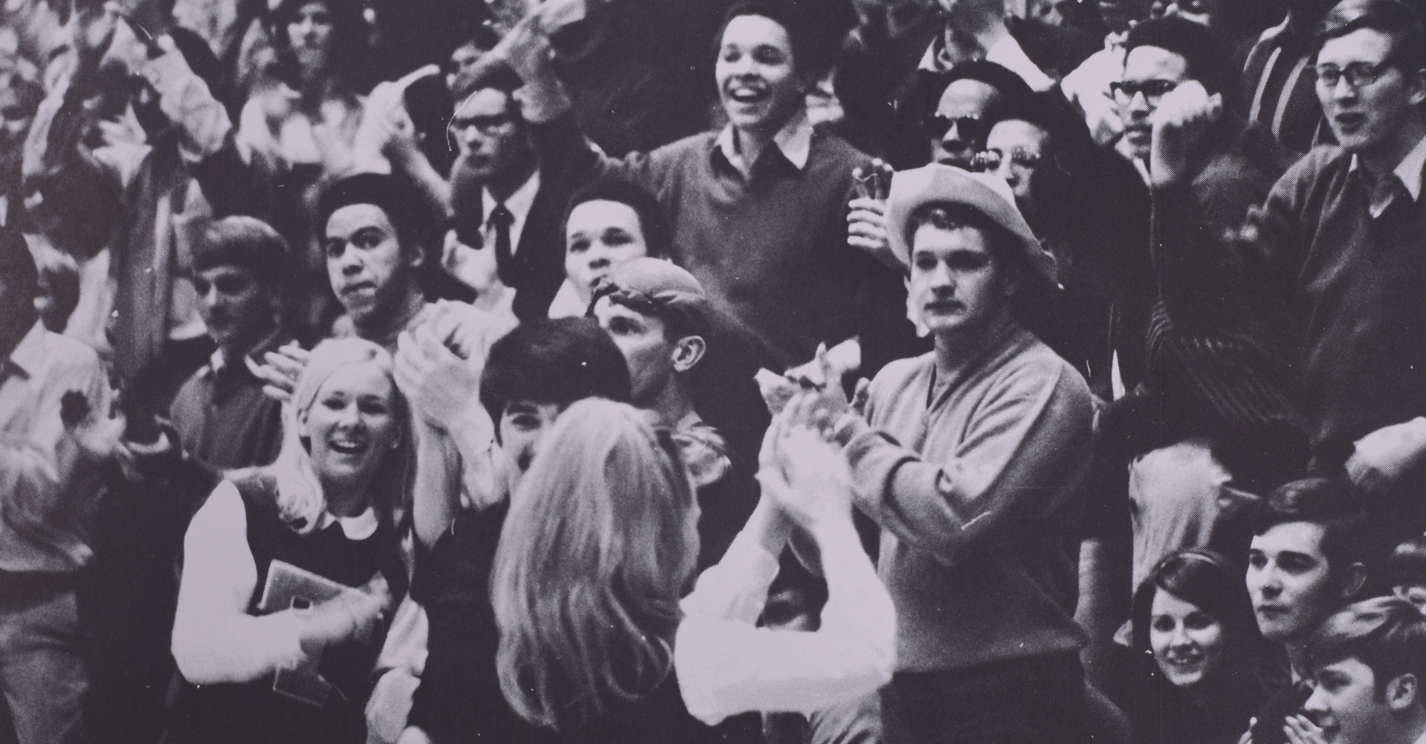 An audience cheers at a pep rally or athletics event.