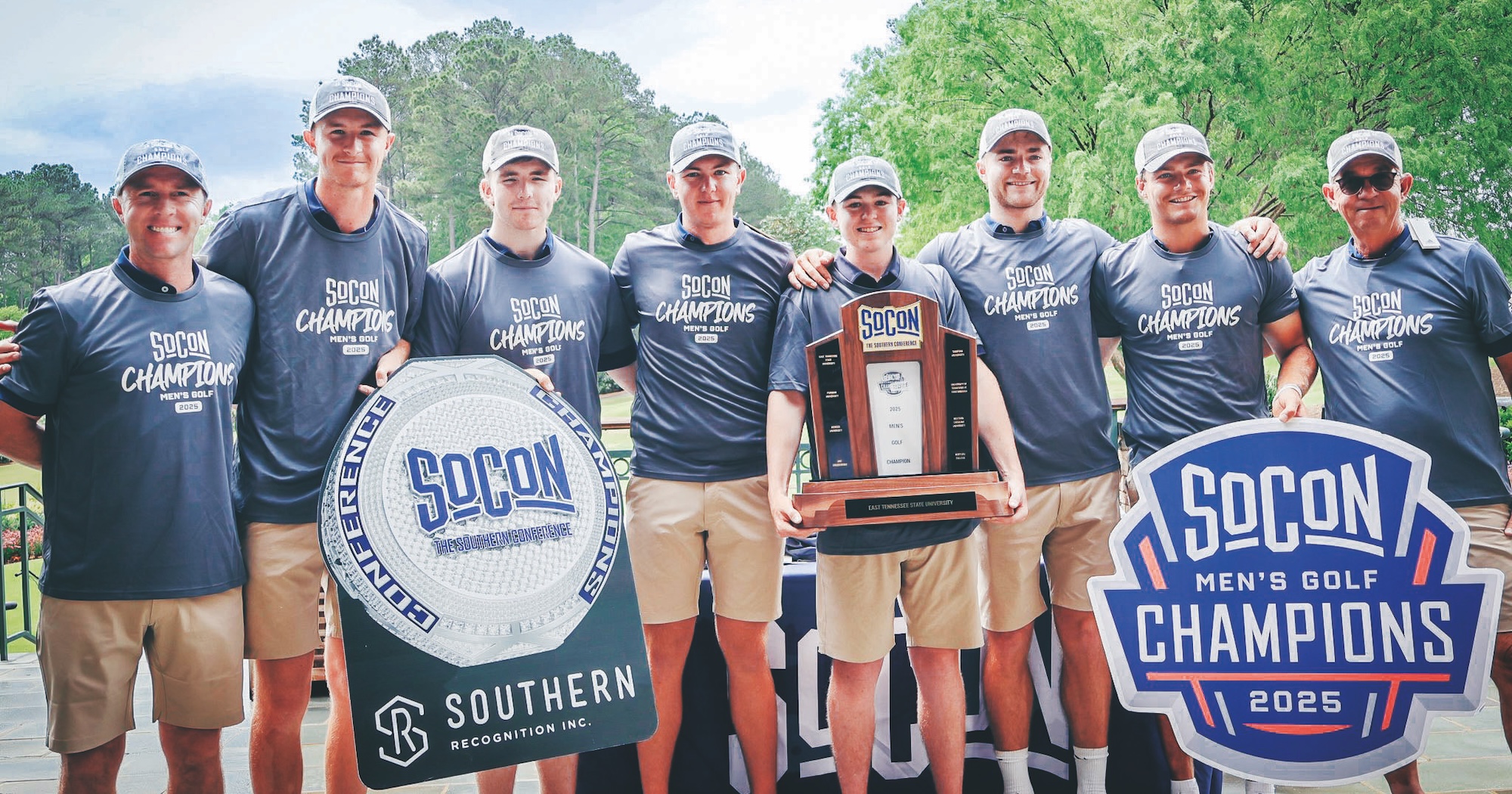 The ETSU golf team poses for a group photo while holding a trophy and the SOCON Champions sign.