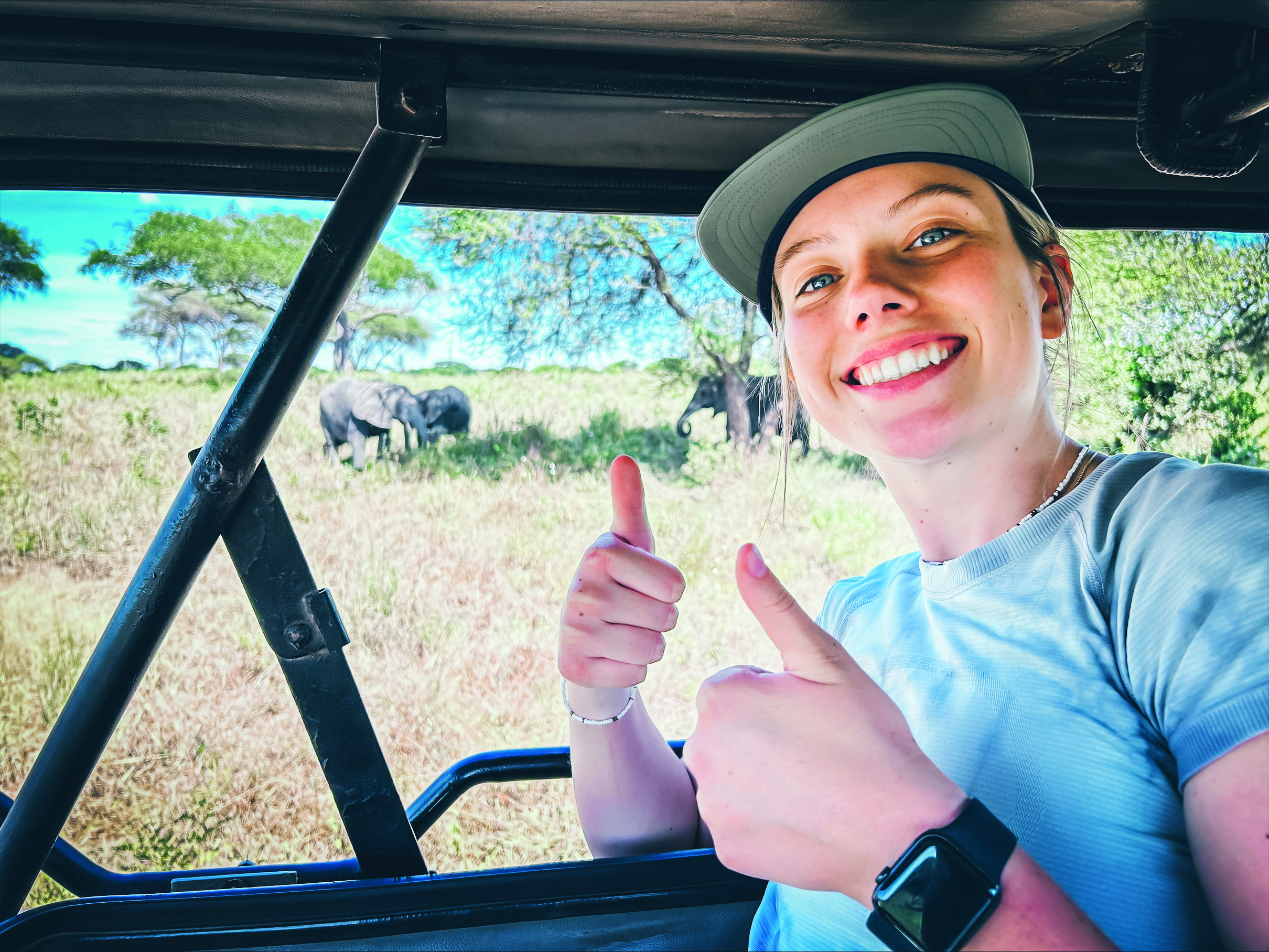 Reagan Sparks gave a thumbs up, with elephants grazing in the background.
