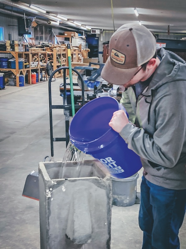 A person pours water from a bucket into another container.