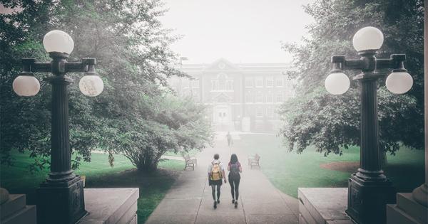 students walk towards Nicks Hall through a fog.