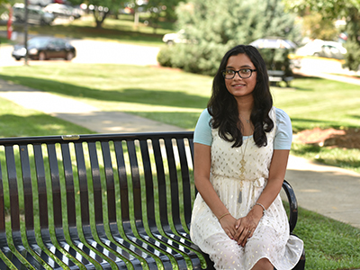 Megha Gupta, pictured seated on bench adjacent to Sherrod Library.