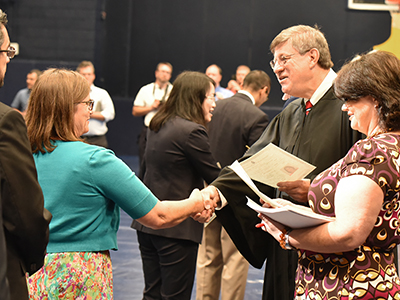 The Honorable J. Ronnie Greer shakes hands with individuals as they receive their certificates of citizenship.