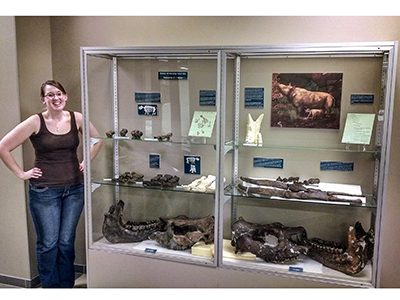 Lead author Rachel Short standing beside a display case she designed for the ETSU Museum of Natural History to teach visitors about the Gray Fossil Site rhinos. This was before the new species was given its new name, Teleoceras aepysoma. (Photo by Jeff Martin)