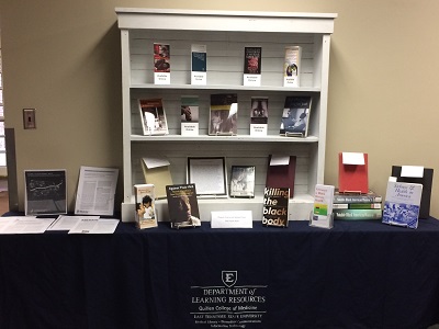 Display table and shelves featuring selected books, journal articles, and information related to medicine and Black History Month