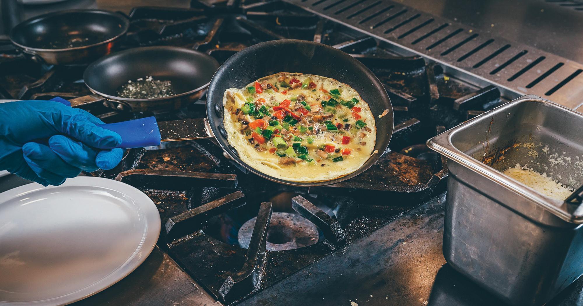 An omelette being prepared over a stove top in the etsu dining hall.